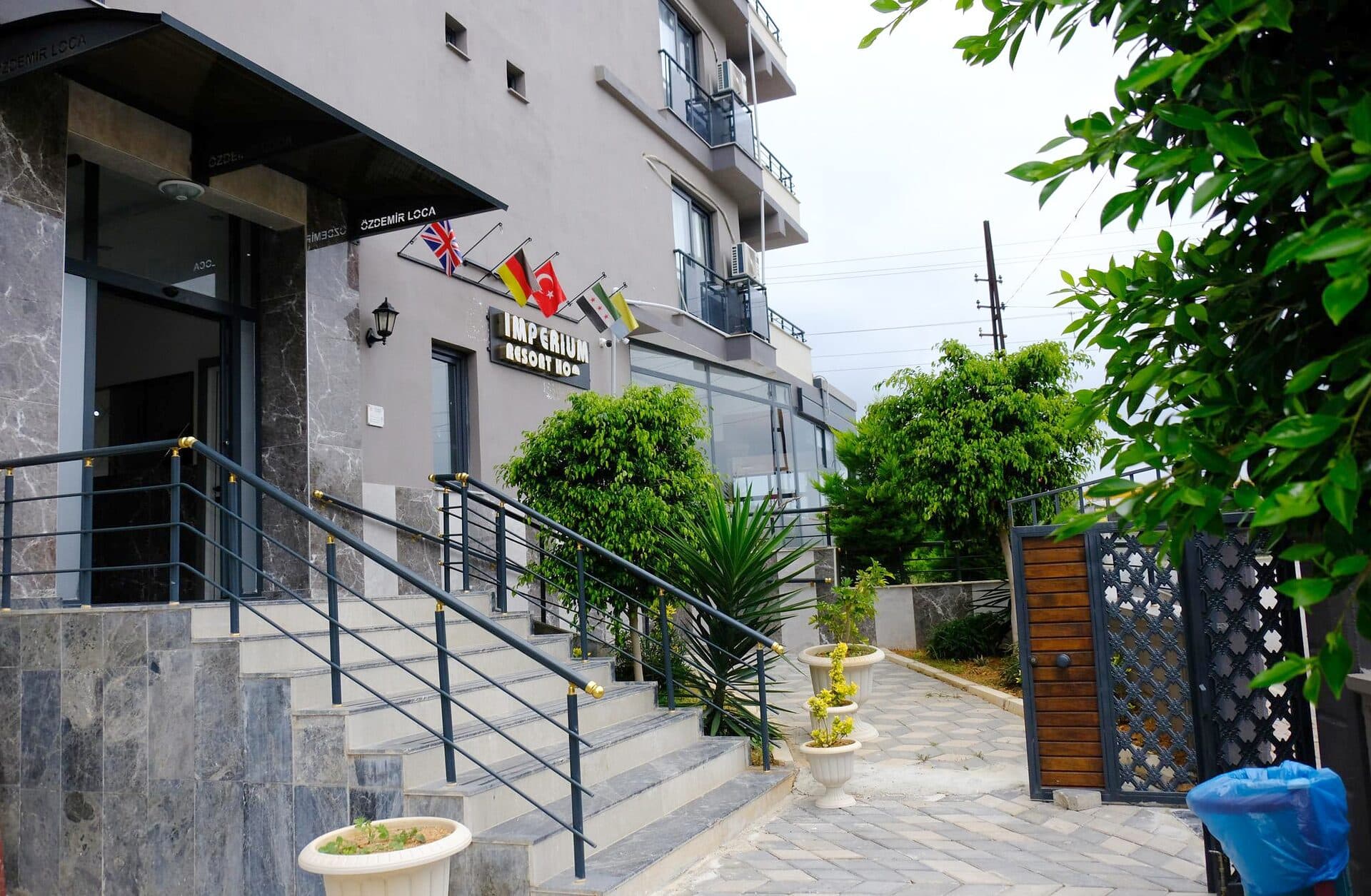 Otelin merdivenli girişi, bayraklar ve yeşillik